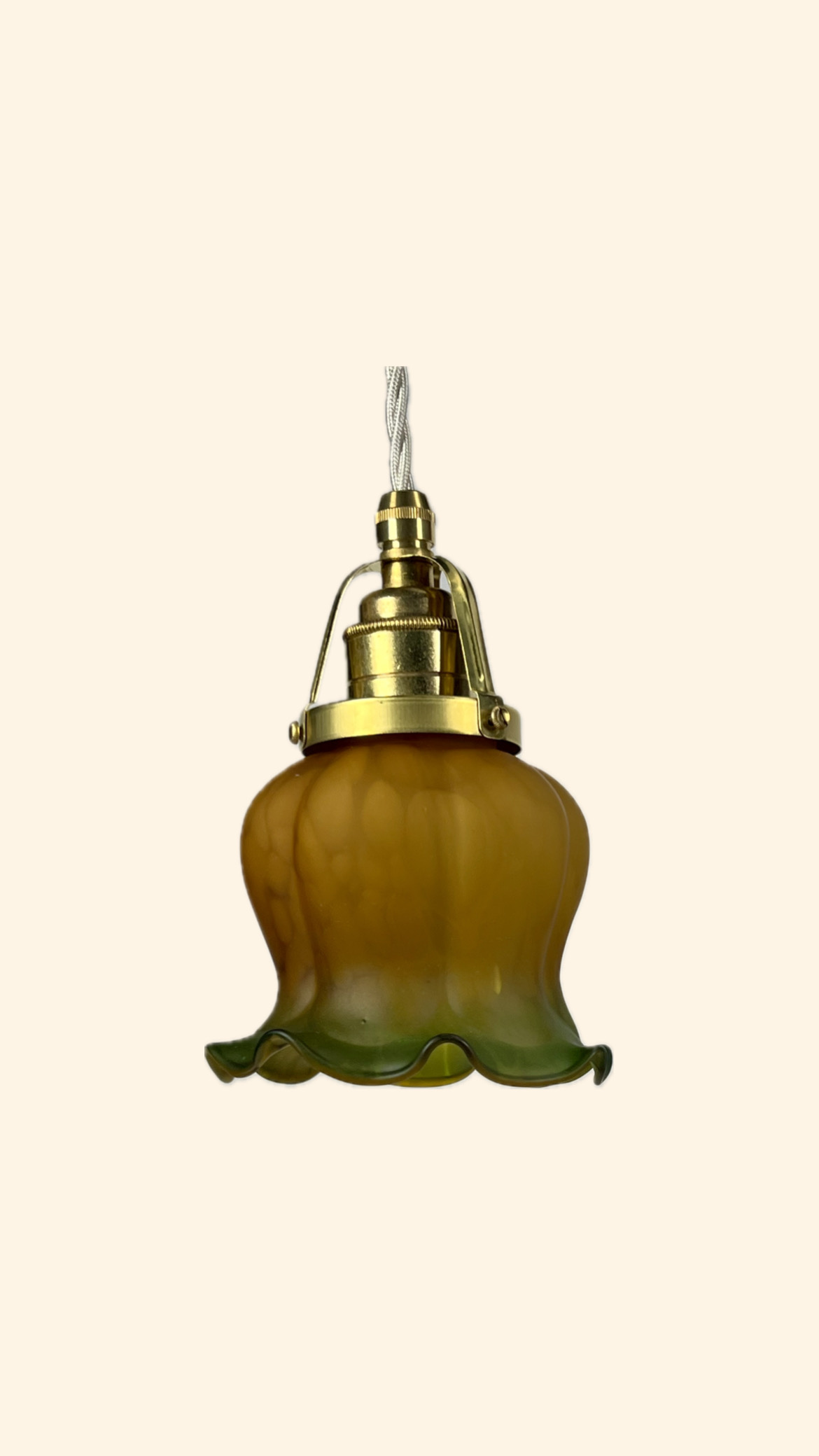 Fönsterlampa hängande i Jugendstil med amberfärgatglas upptill och mörkgrönt färgat glas nertill på volangkanten. 

Skomakarupphäng i Mässing med vit sladd 

Fäste:55mm Höjd:11cm Bred:12cm 
Pris: 380 kr